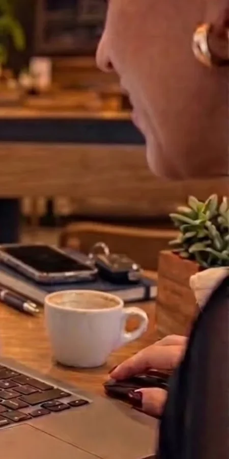 A Dra. Kelli de perfil, com café, revendo no notebook a documentação dos casos